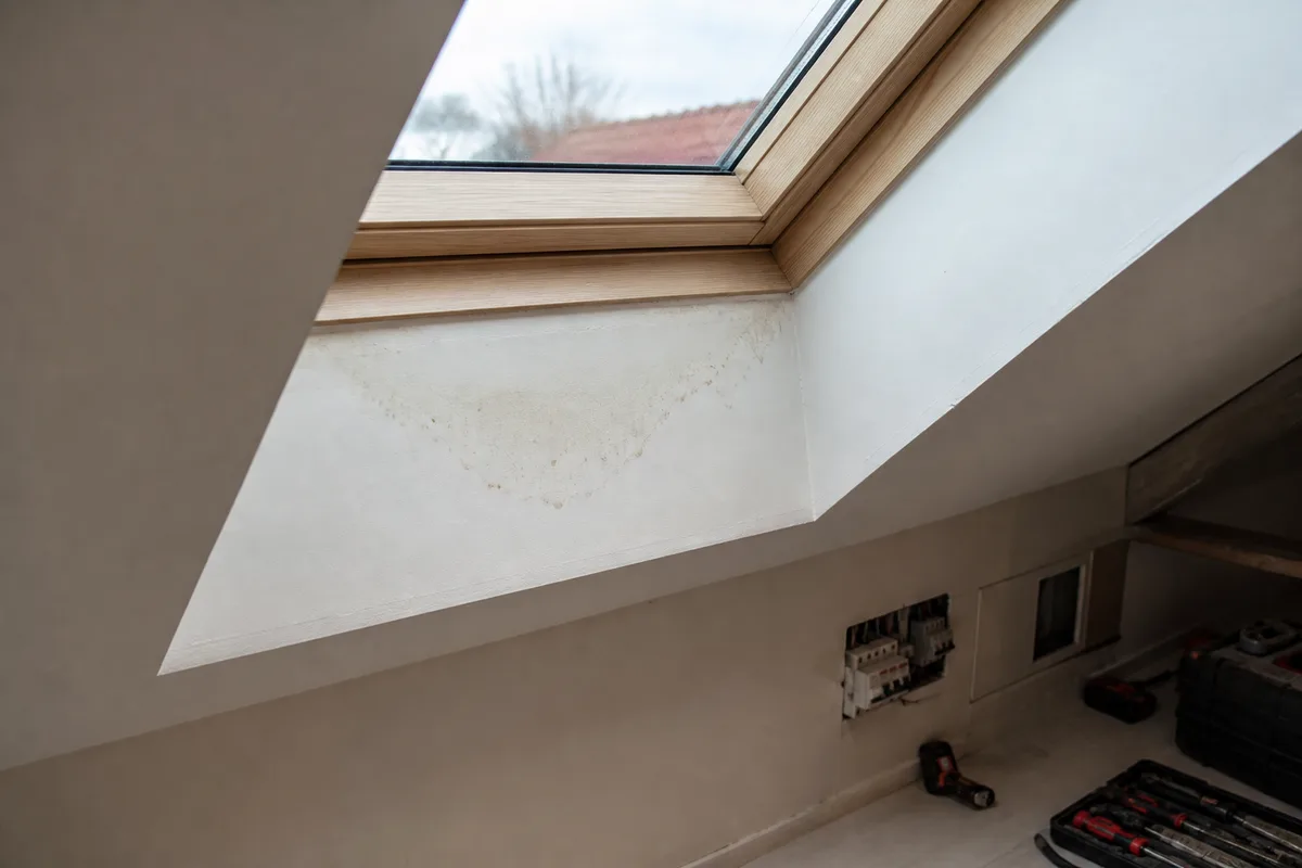 Traces d&rsquo;humidité et auréole sur l&rsquo;habillage intérieur sous une fenêtre de toit, dans une pièce sous combles